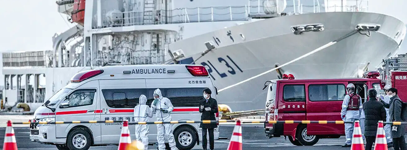 Imagem de um navio de cruzeiro e ambulâncias em volta